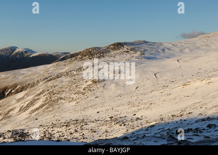 La zona al di sotto del Scafell noto come pietre di cava con il lato di Lingmell ricoperta di neve e inondate di luce della sera. Foto Stock