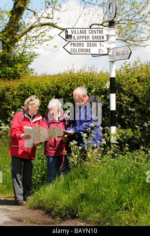 Gruppo di escursionisti in pausa per leggere la loro mappa e verificare la direzione di corsa visto nella campagna dell'Hampshire in primavera Foto Stock