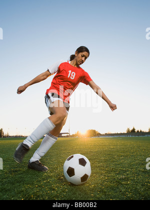 Razza mista donna calci palla calcio Foto Stock