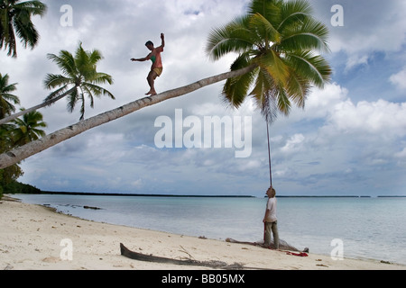 Due turisti rig fino a swing corda dalla fine di una inclinazione di palme da cocco a Ant Atoll, Pohnpei, Stati Federati di Micronesia. Foto Stock
