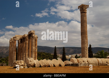 Una colonna che è scesa la posa di fronte standing colonne del tempio di Zeus Olimpio ad Atene in Grecia Foto Stock