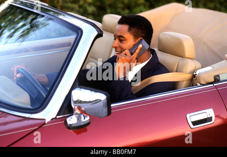 Nero di successo african american business man sul telefono cellulare mentre si è in viaggio nel lusso cabrio Foto Stock