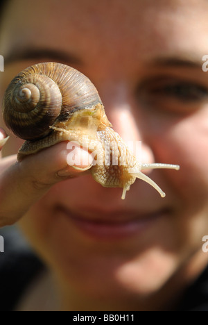 La donna nella sua mano azienda Helix pomatia lumaca giardino in Europa Foto Stock