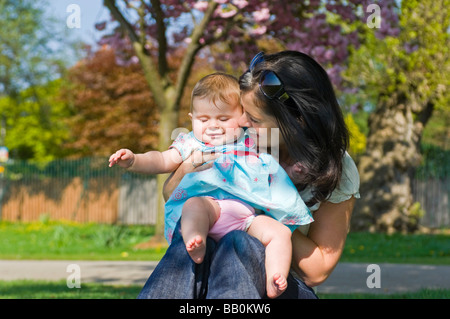 Chiudere orizzontale su ritratto di una giovane mamma parlando affettuosamente a sua figlia del bambino al di fuori nel sole Foto Stock