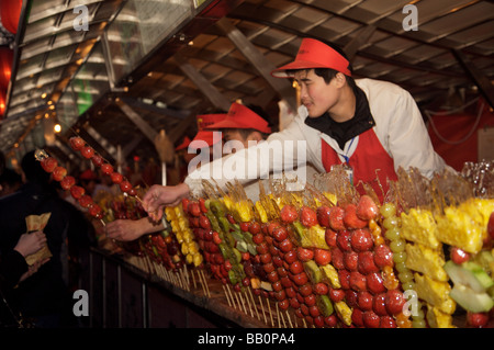 L'uomo la vendita di frutta candita aderisce a un mercato notturno in stallo a Pechino Foto Stock