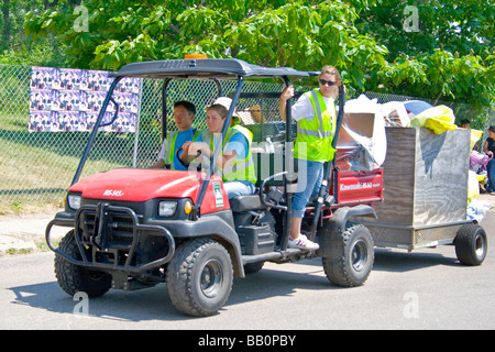 Teens pick up sacchi della spazzatura in Kawasaki MS-545 veicolo con rimorchio. Hmong Sports Festival McMurray campo St Paul Minnesota USA Foto Stock