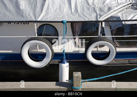 Vecchi pneumatici per auto appeso accanto a una barca Foto Stock