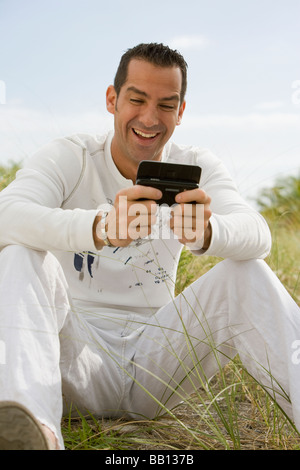 Uomo ispanico ridere del messaggio di testo Foto Stock