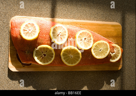 Un filetto di salmone rosso è condito e giacente su un imbevuto di acqua in legno di cedro e pronto per il grill Foto Stock