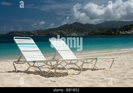 Due vacante di sedie a sdraio su un isola tropicale, coral-spiaggia di sabbia con oceano turchese e il blu del cielo. Foto Stock