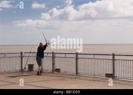 Un uomo pesca in mare la fine di Southwold Pier in Southwold,Suffolk, Regno Unito Foto Stock