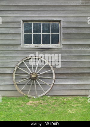 In legno antico ruota carrello sostennero contro il muro del granaio Foto Stock