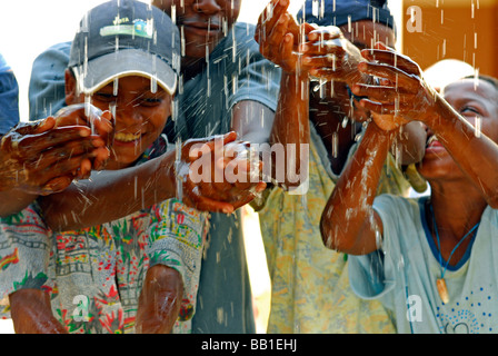 SAO TOME E PRINCIPE S"o TomÈ isola. Nero adolescenti raccolte sorridente e con volti felici lavarsi le mani con gocce di acqua Foto Stock