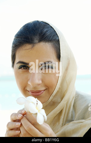 Close up ritratto di donna odorare un fiore, Dubai, UAE Foto Stock