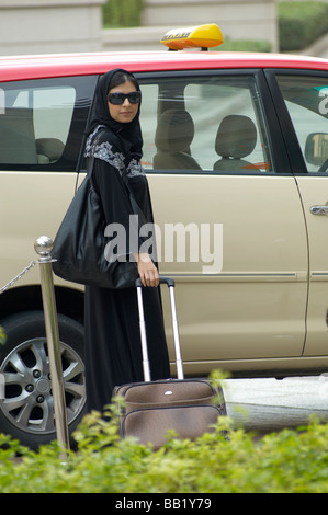 Basso angolo vista di una donna in piedi in taxi con i bagagli, Dubai, UAE Foto Stock