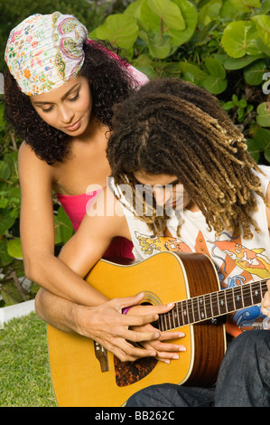 Uomo di insegnamento di una donna come suonare una chitarra Foto Stock