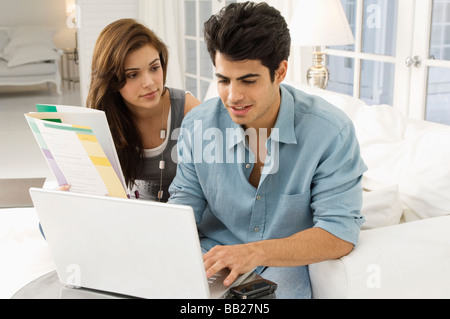 Uomo che utilizza un computer portatile con una donna seduta accanto a lui Foto Stock