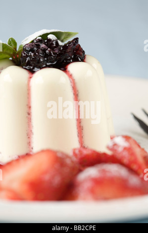 Deliziosa panna cotta guarnita con bacche nere e fragole sul lato Foto Stock