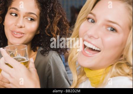 Due donne gustando un drink in un party Foto Stock