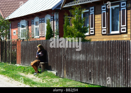 Una vecchia donna seduta su una panchina nel villaggio Soce, Polonia Foto Stock