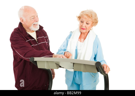 Bello il senior uomo cercando di captare una bella donna su un tapis roulant Lei sta ignorando lui isolato Foto Stock