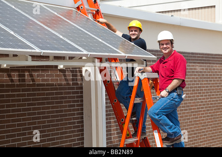 Felice elettricisti impiegato per installare a risparmio energetico pannelli solari nella nuova economia verde Foto Stock