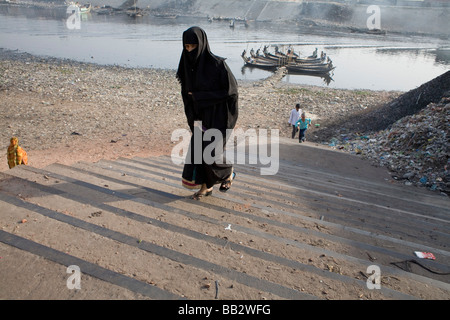 La vita quotidiana in Bangladesh; una donna cammina fino passi indossando un tradizionale burka. Foto Stock