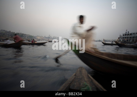 La vita quotidiana in Bangladesh; un uomo è sfocata in movimento come egli righe la sua barca lungo il fiume Buriganga a Dhaka. Foto Stock