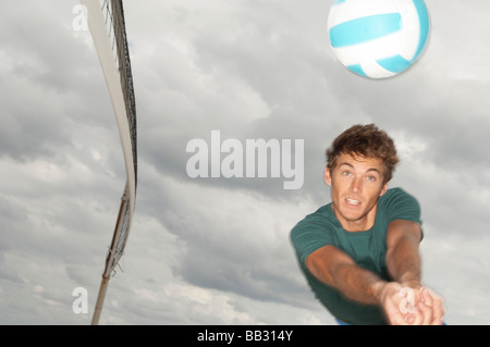 L'uomo giocando a pallavolo sulla spiaggia Foto Stock