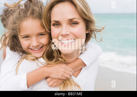 Donna che sua figlia piggyback sulla spiaggia