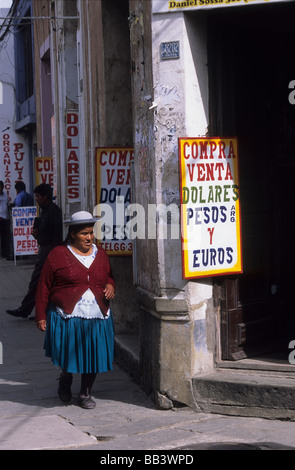 Locali indigene Quechua lady camminando lungo la strada piena di cambiavalute insegne , Tarija , Bolivia Foto Stock