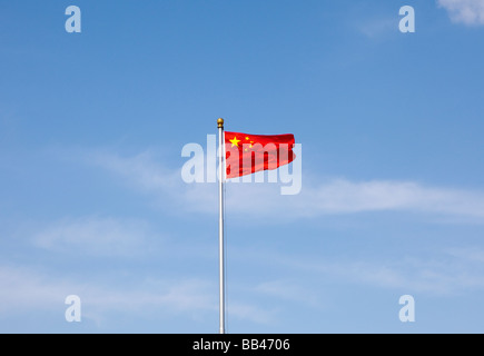 Una bandiera cinese vola contro un cielo blu Foto Stock