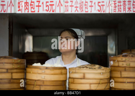 Una donna cinese vende spuntini su un angolo di strada in Xian, Cina. Foto Stock