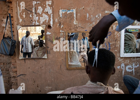 Barbiere dando un taglio di capelli su una strada nel centro di Khartoum, Sudan. Foto Stock