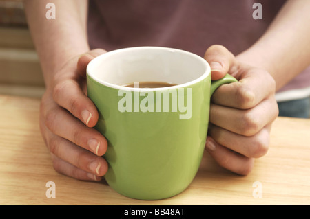 Una coppia di womans mani tenendo una tazza di caffè Foto Stock