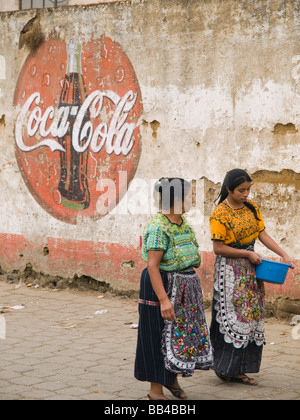 Gli abitanti di un villaggio a piedi passato il logo di coke. Foto Stock