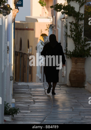 In Europa, in Grecia, Santorini o Thira, Oia. La donna in nero a piedi lungo vuoto stone street. Foto Stock
