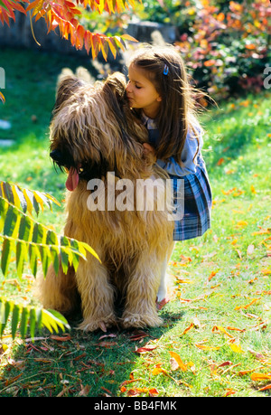 Ragazzina che sussurra nell'orecchio di Briard, cane da pastore grande, giardino, Francia, Europa, Foto Stock