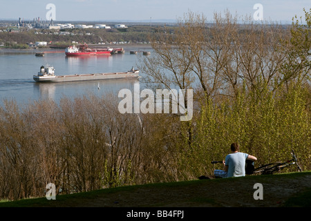 Un uomo a suonare la chitarra sulle pianure di Abramo si preannuncia una nave la navigazione a St Lawrence river come egli passa vicino a una petroliera Foto Stock