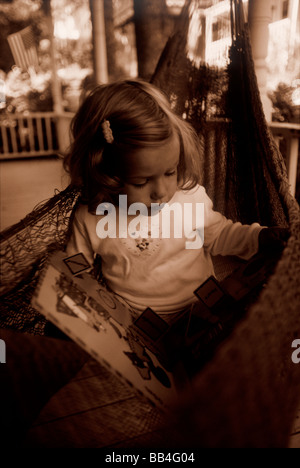 Una giovane ragazza legge un libro immagini al suo cottage estivi in Bayside, Maine su Penobscott, Bay. Foto Stock