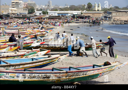 Colorfully dipinto barche da pesca la linea della spiaggia presso il mercato del pesce di Dakar in Senegal Foto Stock
