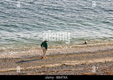 Senior indossando gli zoccoli passeggiate lungo il litorale a Ebey's Landing sul stretto di Juan de Fuca Foto Stock