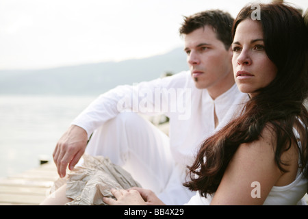 Ritratto di un giovane seduto su di un molo al lago Foto Stock