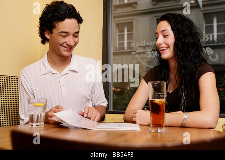 Due teenager a ridere con il menu card Foto Stock