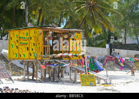 Un negozio di souvenir su palafitte si siede su una spiaggia affollata sulla costa nord di Mombasa, una popolare destinazione turistica. Foto Stock