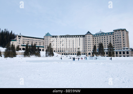 Il Fairmont Chateau Lake Louise hotel circondato da montagne coperte di neve e di fronte al lago ghiacciato Foto Stock