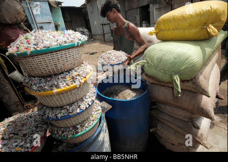 Cestini di trucioli di plastica essendo lavato dal giovane lavoratore indiano nella baraccopoli di Dharavi Foto Stock