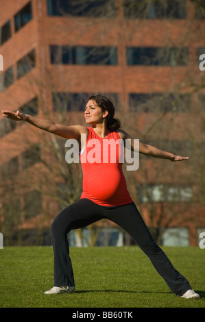 Medio incinta donna orientale a praticare yoga in posizione di parcheggio Foto Stock