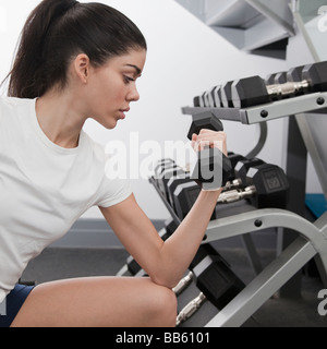 Donna ispanica utilizzando i pesi a mano nel club salute Foto Stock