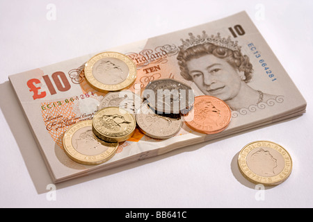 Nuovo e inutilizzato batuffolo di sterline inglesi dieci pound banconote con coniare monete giacente sulla parte superiore Foto Stock
